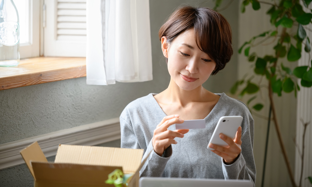 クレカを見ながらスマホを操作する女性